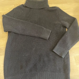 Svart stickad polotröja från H&M - Säljer en svart stickad polotröja från H&M. Tröjan har lång ärm, ribbad struktur och hög polokrage. Perfekt för kyliga dagar och enkel att matcha med olika outfits.