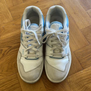 New Balance 550 sneakers i vitt och ljusblått - Säljer ett par New Balance 550 sneakers i vitt och ljusblått. Skorna har klassisk snörning, rund tå och platt sula. Bekväma och snygga sneakers till vardags. 