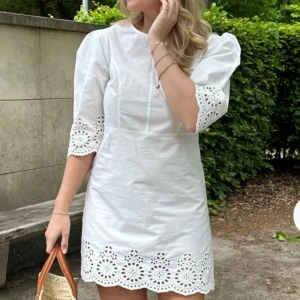 Vit kortklänning med broderade detaljer - Superfin vit kortklänning med puffärm. Passar perfekt nu till sommarn eller till studenten!! Klänningen har aldrig använts och har prislappen kvar😍