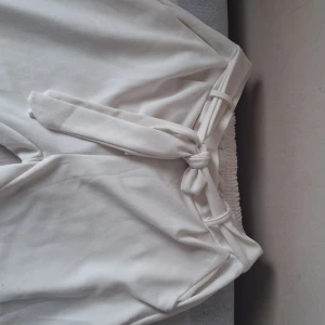 Vita byxor med bälte i midjan - Snygga vita byxor med hög midja och avtagbart bälte i midjan. Byxorna har raka ben och är tillverkade i ett mjukt material med lite stretch. Perfekta för en stilren look. Perfekt för sommaren. Dom här kan användas som line byxor dom e köpta från new yorker för 175 