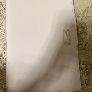 Ljusrosa datorväska från Ideal of Sweden - Säljer en stilren ljusrosa datorväska från Ideal of Sweden med diskret logga i metall på framsidan och en smal dragkedjeficka på baksidan. Väskan är rektangulär och passar perfekt för laptop eller dokument. Se mått på bilderna!🥰Knappt använd❤️