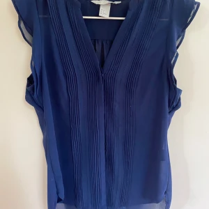 Mörkblå blus/topp med veckade detaljer från H&M - Jättefin men har tecken på användning och en lite fläck, detta syns dock ej när den används