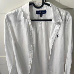 Vit linneskjorta från Ralph Lauren - Klassisk vit skjorta i linne från Ralph Lauren med lång ärm och broderad logga på bröstet. Storlek L(14-16).