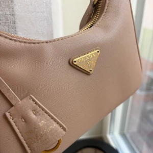 Prada re-edition - Säljer nu min älskade Prada re-edition väska, den är i en dammrosa färg (ej färgskillnad i verkligheten ljuset på bilderna spökar). Den är använd väl men med kärlek så den är i väldigt gott skick. Box, verifikationskort osv ingår självklart! Lägre pris då kvittot tappats bort, köpt på mytheresa. Skriv för mer bilder 💛 nypris i butik idag ca 25 000