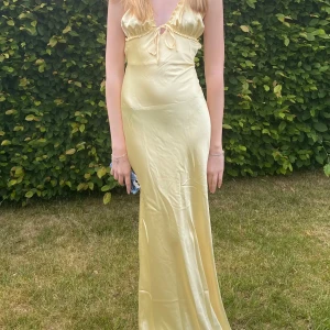 Ljusgul långklänning i satin - Säljer denna långklänning. Den är i modellen tall och jag är 180 cm lång. Den har även en dragkedja på ryggen. 
