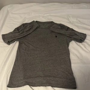Grå långärmad T-shirt från Polo Ralph Lauren - Säljer en grå långärmad T-shirt från Polo Ralph Lauren med klassisk passform och liten broderad logga på bröstet. Den långärmade T-shirten är långärmad och tillverkad i mjuk bomull, perfekt för en avslappnad stil.