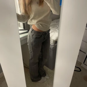 Gråa lågmidjade jeansbyxor - Säljer ett par gråa jeansbyxor med låg midja och raka ben. Klassisk femficksmodell med dragkedja och knapp framtill. Jeansen har en avslappnad passform och är perfekta för en casual eller clean stil. Dessa är har suverän kvalitet då de endast används en gång!