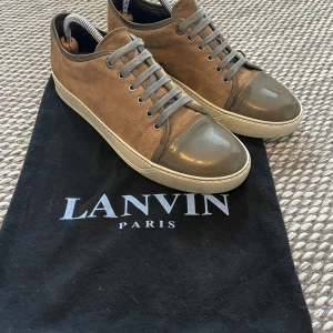 Lanvin UK 7 - Säljer ett par snygga sneakers från Lanvin i brunt mocka med grå/mörkgrön toecap fint skick, såklart äkta! Enda lilla defekten är att dem blivit lite creasade på toecapen annars fint skick! priset är ganska lågt eftersom att jag vill sälja skorna fort, Tar byten, först till kvarn! Pris går att diskutera lite vid snabba affärer!