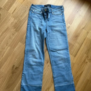 Blå jeansbyxor från Liverpool - Snygga blå jeansbyxor från Liverpool med klassisk femficksdesign och raka ben. Byxorna har dragkedja och knapp framtill samt bälteshällor. Modellen är croppad och har en straight fit som ger en avslappnad look.