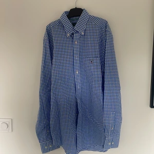 Blårutig skjorta från Gant - Säljer en klassisk blårutig skjorta från Gant i regular fit. Skjortan har knappar framtill, bröstficka med broderad Gant-logga och button-down krage. Perfekt för dig som gillar stilrena och tidlösa plagg. Storlek S.