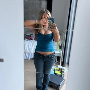 Turkos croppad linnetopp med spetsdetaljer - Säljer en turkos croppad linnetopp med smala axelband och spetsdetaljer vid urringningen. Toppen har en tight passform och är perfekt för varma dagar.