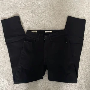 Svarta Levi's 724 High Rise Straight jeans - Svarta jeans från Levi's modell 724 High Rise Straight. Klassisk femficksmodell med raka ben och hög midja. Perfekta svarta jeans för dig som gillar en tidlös och stilren look.