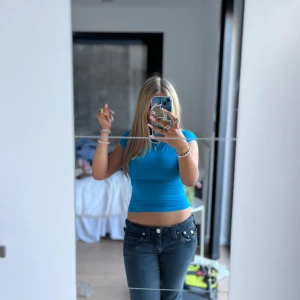 Blå croppad topp med öppen rygg - Säljer en blå croppad topp med tight passform och öppen rygg. Toppen har korta ärmar och är tillverkad i ett stretchigt material som sitter snyggt på kroppen. Perfekt för dig som vill ha en trendig och bekväm topp.