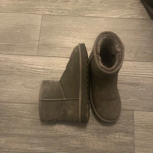 Gråa uggs - Säljer ett par gråa uggs med mjukt foder. Perfekta för kalla dagar med sin varma insida och robusta design. De har en enkel och stilren look som passar till det mesta.
