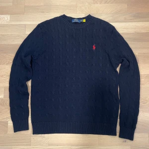 Mörkblå kabelstickad tröja från Ralph Lauren - Säljer en stilren mörkblå kabelstickad tröja från ralph Lauren, 10/10 skick som passar till allt. Tröjan är i storlek S och kommer till 100% ge dig massor av komplimanger. 