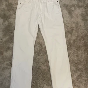 Vita low straight jeans - Snygga vita jeans med låg midja och rak passform. Perfekta för en stilren look. De har klassiska fem fickor och en knappgylf.