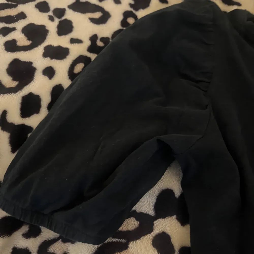 Säljer en stilren svart topp med puffärmar. Toppen har en normal passform och är perfekt för både vardag och fest. Den är tillverkad i ett mjukt material som ger en bekväm känsla hela dagen.. Yläosat.