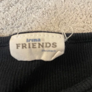 Svart ribbad tröja från Irma Friends - Säljer en svart ribbad tröja från Irma Friends. Tröjan har långa ärmar och en enkel design som passar perfekt till vardags. Den är mjuk och bekväm med en rund halsringning. Toppen är också väldigt kort