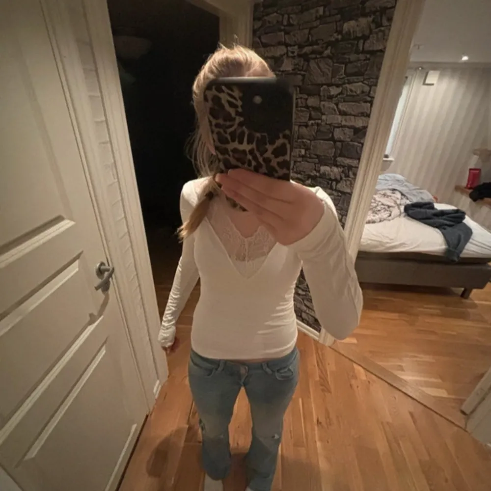 Säljer en stilren vit långärmad topp från Gina Tricot med v-ringning och spetsdetaljer. Perfekt för en elegant look. Passar bra till jeans eller kjol.. Neuletakit & Villapaidat.