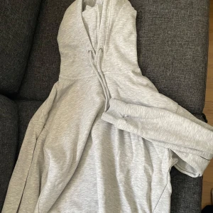Grå hoodie - Säljer en bekväm grå hoodie med justerbar dragsko i huvan. Tröjan har långa ärmar och en klassisk passform. Aldrig använd.