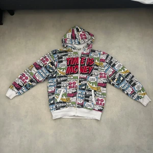 Zipup  - Cool hoodie med textmönster i olika färger som röd, blå, gul och grön. Texten 'Time is Money' står ut i rött. dragkedja och huva, perfekt för en avslappnad stil. 