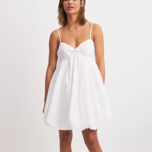 Vit kortklänning med knytband - Säljer en vit klänning med knytband på axlarna. Helt oanvänd, endast testad (hann inte returnera). Från Nakd. Perfekt studentklänning!! Kostar 600kr på hemsidan.