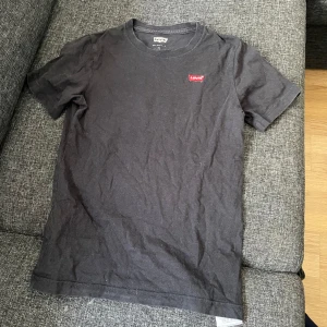 Svart t-shirt från Levi's - Säljer en klassisk svart/marinblå t-shirt från Levi's med en liten röd logga på bröstet. T-shirten har en normal passform och är kortärmad. Storleken på tröjan är barnstorlek 156-158