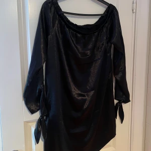 Svart klänning - Snygg svart offshoulder klänning med långa ärmar och knytband vid ärmsluten. lite nopprig