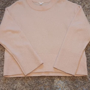 Ljusrosa stickad tröja från Gina Tricot - Mysig ljusrosa stickad tröja från Gina Tricot. Tröjan har långa ärmar och ribbade detaljer vid ärmslut och nederkant. Perfekt för kyligare dagar! Lite nopprig vid armarna och längst ner.