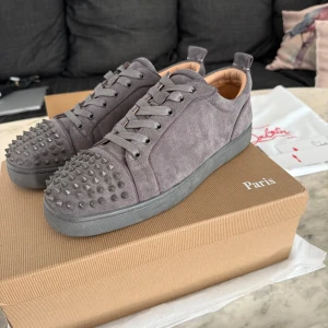 Mörkgråa Louboutins med mocka - Hej! Säljer mina louboutins då de var för stora för mig. Det är storlek 43. Jag har legit checkat dem, och de verkar vara äkta! Skicket på skorna är 8/10 de har används någon månad så de är pytte lite slitna men inget man märker! Som ni ser på sista bilden så saknas det nån knapp på sidan av skon, men tror inte de ska vara någon konstighet att beställa sånna på nätet och de är nog inte dyra heller! Priset är diskuterbart. Har du någon fråga så är det bara till att skicka ett dm! Mvh Oscar 