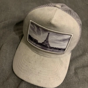 Grå Keps från Rovior - Rovior keps med Eiffeltornet motiv! Använd ett fåtal gånger. Mycket bra skick! Nypris 449 kronor! Mitt pris 99 kr! Tveka inte på att höra av er! Kan gå ner i pris vid snabb affär! Kan köpa med de andra kläderna för ett billigare pris! 