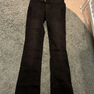 Svarta bootcut jeans från H&M - Snygga svarta bootcut jeans från H&M med hög midja. Perfekta för en stilren look. De har en klassisk design med dragkedja och knapp framtill. 