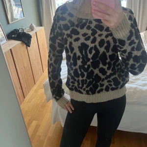 Beige och svart leopardmönstrad stickad tröja - Säljer en snygg stickad tröja med leopardmönster i beige och svart. Tröjan har långa ärmar och ribbade muddar vid ärmslut och nederkant. Perfekt för en trendig look! Kan diskutera priser 🐆