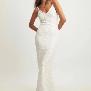 Vit balklänning med blommor och öppen rygg - Elegant vit långklänning i spets med smala axelband och öppen rygg. Perfekt för balen och klänningen har blommdetaljer ock öppen rygg samt en v ringning. Jätte bra skick 💓