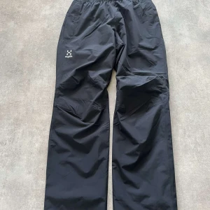 Svarta byxor från Haglöfs - Säljer ett par svarta byxor från Haglöfs. De är tillverkade av 100% återvunnen polyester och har en elastisk midja för extra komfort. Perfekta för utomhusaktiviteter med sin funktionella design. Aldrig använda! 