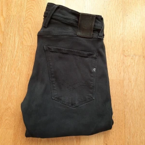 Svarta Replay Anbass jeans - Säljer dessa snygga svarta jeans från Replay med klassisk femficksdesign. De har en stilren look med en diskret logga på bakfickan och en läderpatch vid midjan. Modell anbass : slim fit & storlek 29/32. Vid minsta fundering skriv ett medelande!🙌