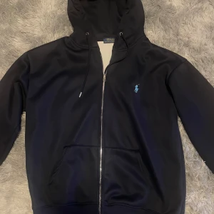 Mörk blå zip hoodie Polo Ralph Lauren - Snygg zip hoodie från Polo Ralph Lauren med dragkedja och det klassiska broderade logotypen på bröstet. 