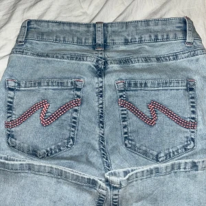 Ljusblå bootcut jeans från Nelly - Ljusblå lågmidjade jeans från Nelly med rosa detaljer på fickor och i sömmen. Säljer då de ej passade mig och inte längre går att skicka tillbaka, helt oanvända 🩷