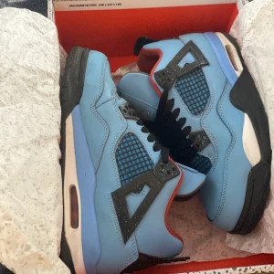 Nike Air Jordan 4 Retro NRG blå - Säljer ett par Nike Air Jordan 4 Retro NRG i blå mocka med svarta och röda detaljer. Skorna har svart snörning, meshpaneler och ikonisk Jumpman-logga på plösen och hälen. Snygg kontrast mellan den ljusblå ovandelen och den svarta sulan. Perfekta för dig som vill sticka ut.