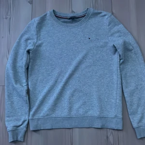 Ljusgrå sweatshirt Tommy Hilfiger Xs: mer som S - En stilren ljusgrå sweatshirt från Tommy Hilfiger i storlek XS. Tröjan har rund halsringning, ribbade muddar och diskret broderad logga på bröstet. Perfekt för en clean och avslappnad look.