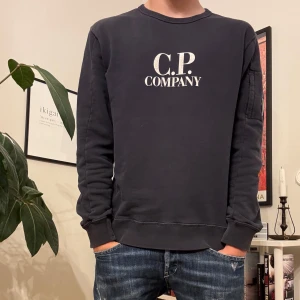 Mörkblå sweatshirt från C.P. Company - Tja! Säljer nu min cp company tröja. Den är använd men är fortfarande i bra skick utan några större defekter. Tröjan är i barnstorlek men sitter bra på mig som är 175. Hör av er om ni har några frågor eller funderingar!