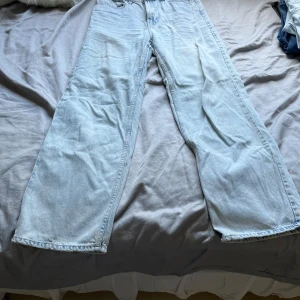 Ljusblåa wide jeans - Säljer ett par ljusblå jeans med riktigt breda ben och klassisk femficksdesign. Jeansen har en avslappnad passform och är tillverkade i mjukt denimtyg. Perfekta för dig som gillar en loose och trendig stil.