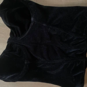 Svart sammetskorsett från ASOS DESIGN - Säljer en svart sammetskorsett från ASOS DESIGN. Toppen är axelbandslös och har en snygg silvrig dragkedja baktill och markerade kupor framtill. Mjuk sammet ger en lyxig känsla och den figurnära passformen samt korsettpinnarna framhäver midjan. 