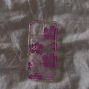 Rosa blommor mobilskal - Säljer ett fint mobilskal till iPhone 13 mini med rosa blommor på med genomskinlig bakgrund. Kommer inte till användning längre. Kontakta gärna innan köp!