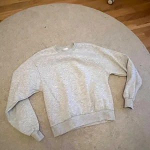 Ljusgrå basic sweatshirt - Enkel och stilren ljusgrå sweatshirt med rund halsringning och långa ärmar. Tröjan har en relaxed passform och breda muddar vid ärmslut och nederkant. Perfekt för en chill och avslappnad look.