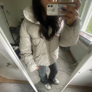 Beige pufferjacka med huva - Säljer en beige pufferjacka med huva och dragkedja framtill. Jackan är fluffig och har en oversized passform som ger en chill vibe. Perfekt för kalla dagar när du vill hålla dig varm och ändå se snygg ut. Passar till allt och är superenkel att styla. Kan alltid diskutera pris. Skriv för frågor och bilder🥰🥰