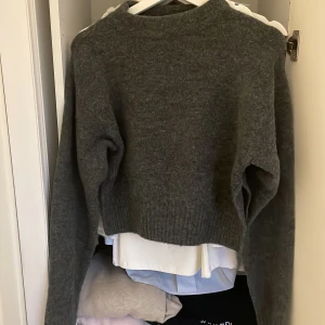 Mörkgrå stickad tröja från Zara - Mysig mörkgrå stickad tröja från Zara i storlek S. Tröjan har en croppad passform, långa ärmar och ribbade muddar vid ärmslut och nederkant. Perfekt för ett par lågmidjade jeans. Den är jättemjuk och jätte skön. Perfekt till hösten och vintern.