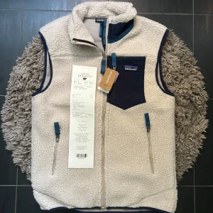 Patagonia Retro-X fleeceväst beige/blå - Säljer en helt ny Patagonia Retro-X fleeceväst i beige med marinblå detaljer. Västen har hel dragkedja, tre fickor med dragkedja och en bröstficka med logga. Tillverkad i återvunnen polyesterfleece, perfekt för lager-på-lager och outdoor-vibe.