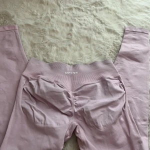 Ljusrosa seamless leggings från DFYNE - Säljer ett par ljusrosa seamless leggings från DFYNE med hög midja och ribbad linning. De har scrunch-detalj bak för extra shaping och är tillverkade i ett stretchigt material som passar perfekt till träning eller chill.