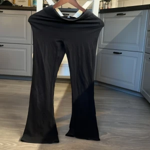 Svarta bootcut byxor i stretch - Svarta byxor i stretchigt material med bootcut-ben. Snygg, enkel design som passar till det mesta. Mjuka och bekväma med hög midja och raka sömmar. Perfekta för dig som gillar en stilren look med lite utsvängda ben.